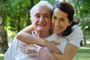 woman hugging older man around the shoulders from behind