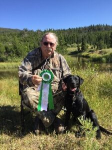 Man posing with ribbon award and dog